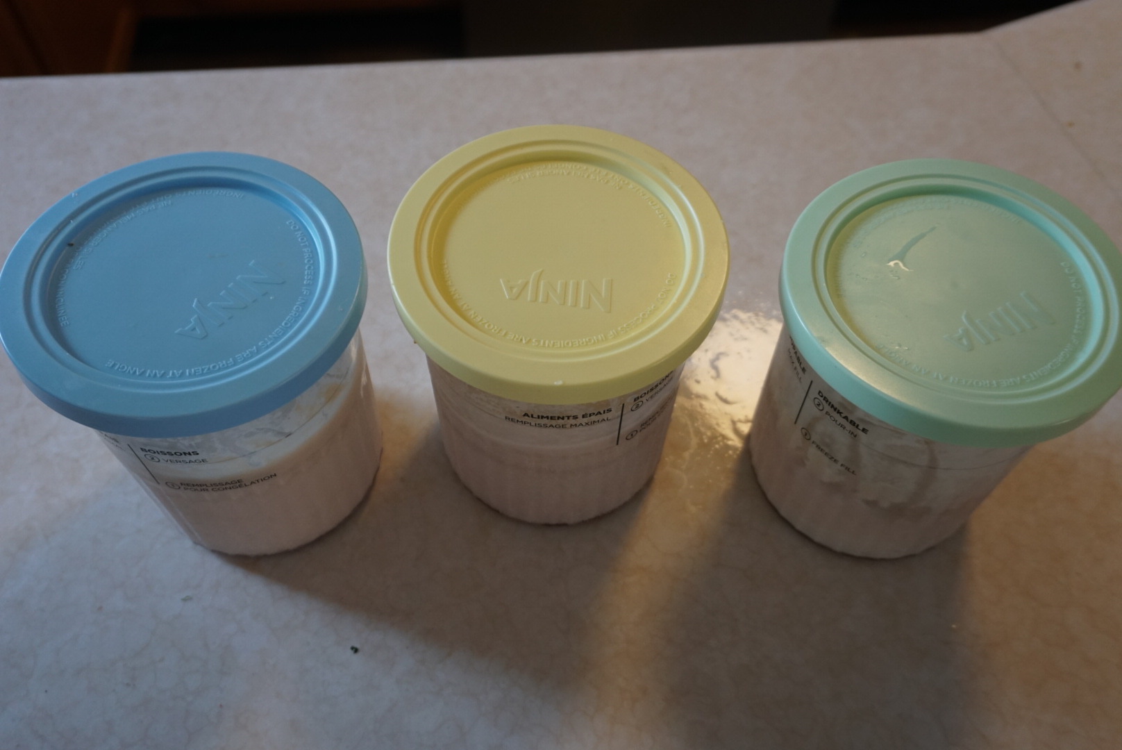 three ice cream Ninja Creami containers with lids on